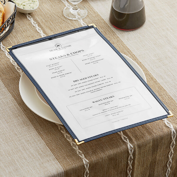 A blue H. Risch, Inc. menu cover on a table with wine glasses and a plate.