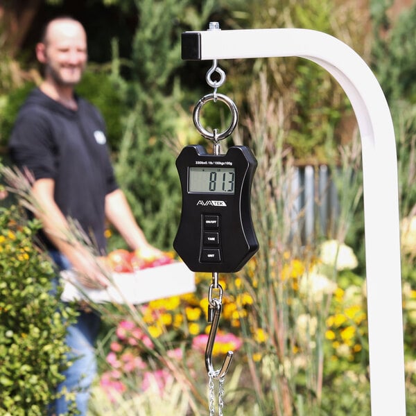A digital hanging scale with a hook, displaying a weight measurement on its screen.