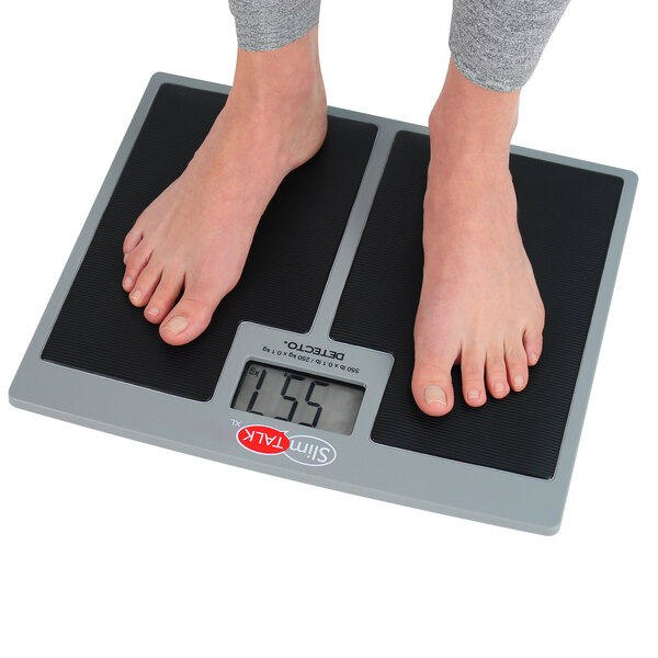 A person standing on a Cardinal Detecto SlimTALKXL low-profile digital scale.