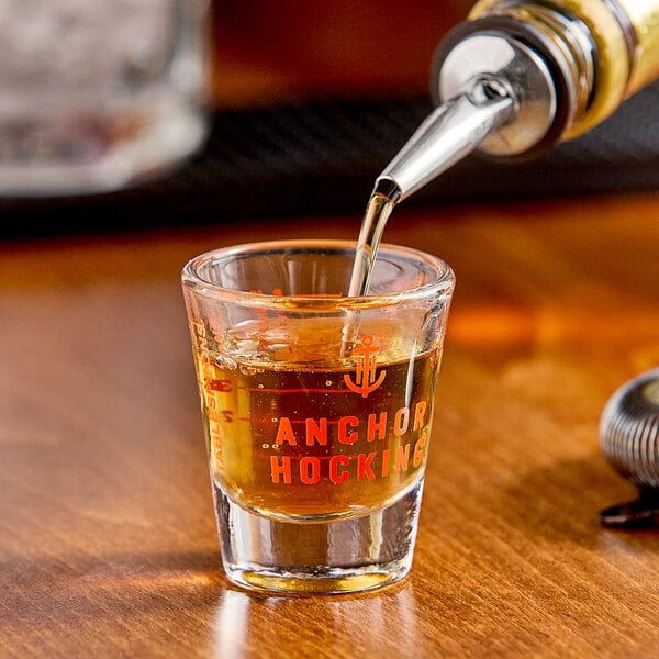 An Anchor Hocking measuring glass filled with brown liquid on a table.