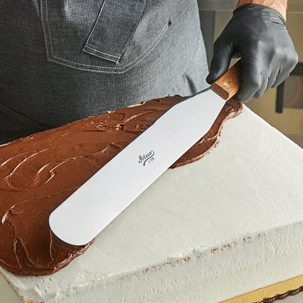 A person using an Ateco straight spatula to frost a cake.