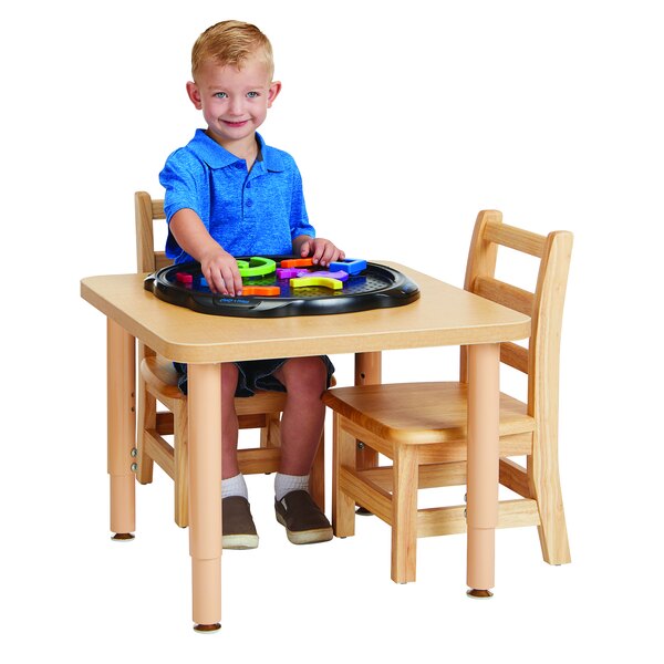 A boy sitting at a Jonti-Craft square table playing with a toy.
