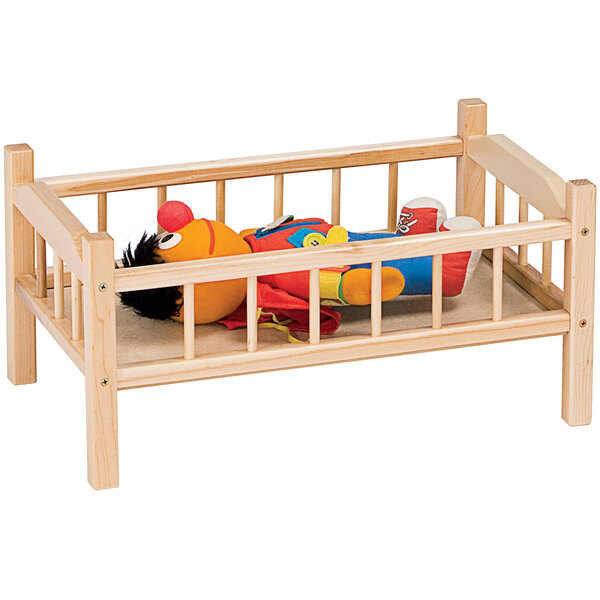 A wooden doll bed with a stuffed animal inside.