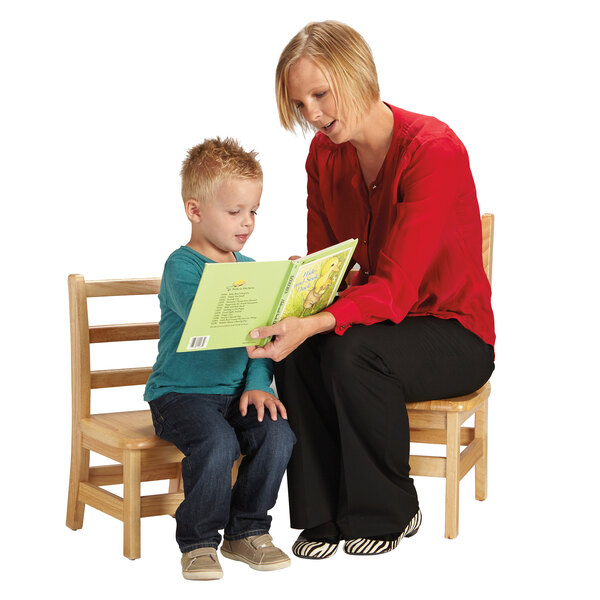 A woman reading a book to a child sitting on a Jonti-Craft Baltic Birch Instructor's Ladderback Chair.