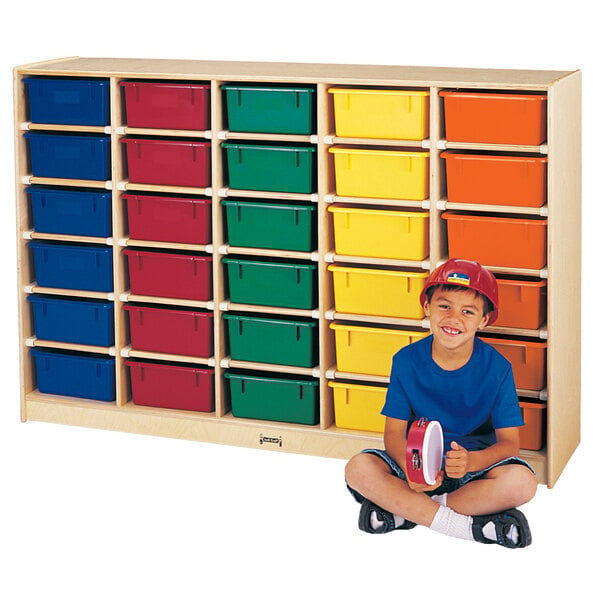 A boy sitting in front of a Jonti-Craft wood storage unit with clear tubs.