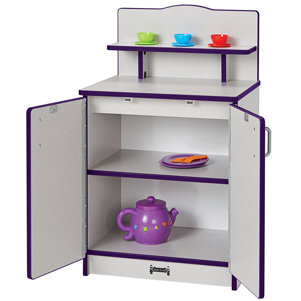 A purple and white Rainbow Accents toy kitchen cabinet with a cupboard and teacups inside.
