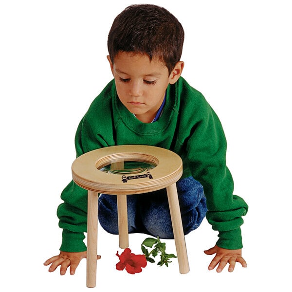 A young boy using a Jonti-Craft children's wood magnifier.