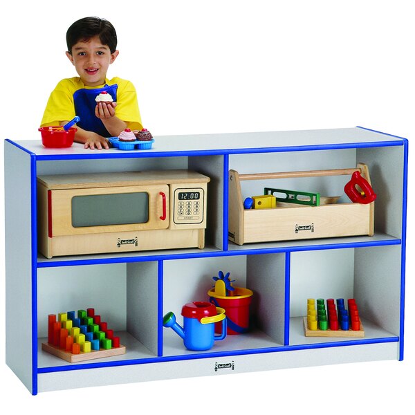 A young boy standing behind a Rainbow Accents blue and gray storage cabinet filled with toys.