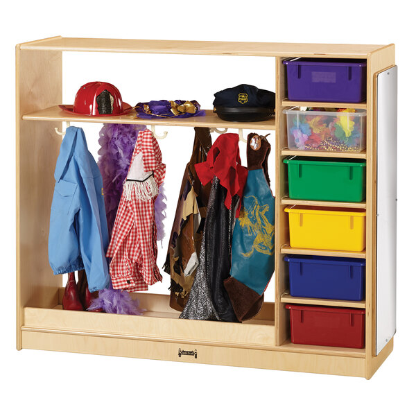 A Jonti-Craft wood storage cabinet with colored trays holding children's clothes and hats.