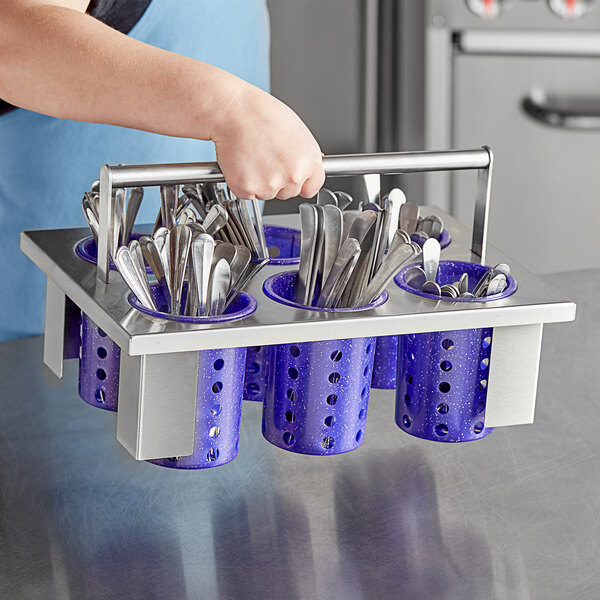 A person holding a metal rack with purple Steril-Sil plastic containers of silverware.