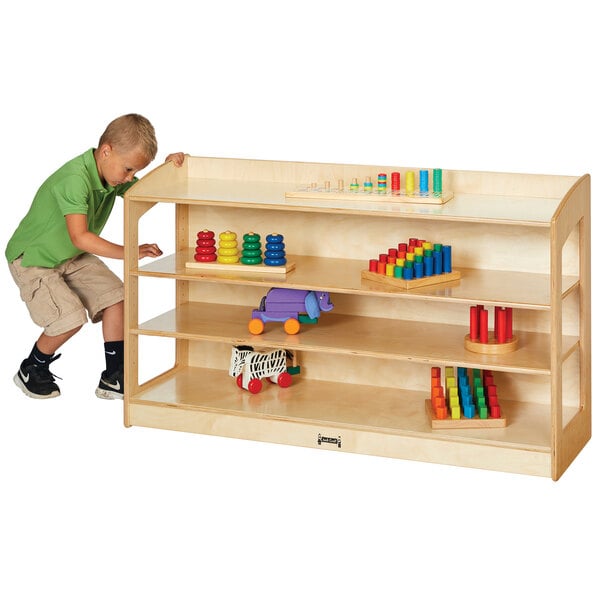 A young boy pushing a Jonti-Craft wood storage cabinet.