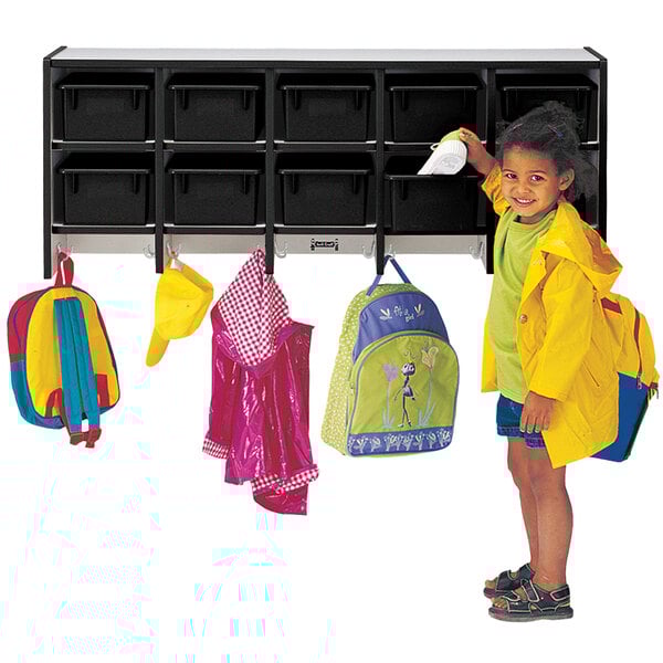 A little girl standing next to a Rainbow Accents black laminate coat rack with double hooks.