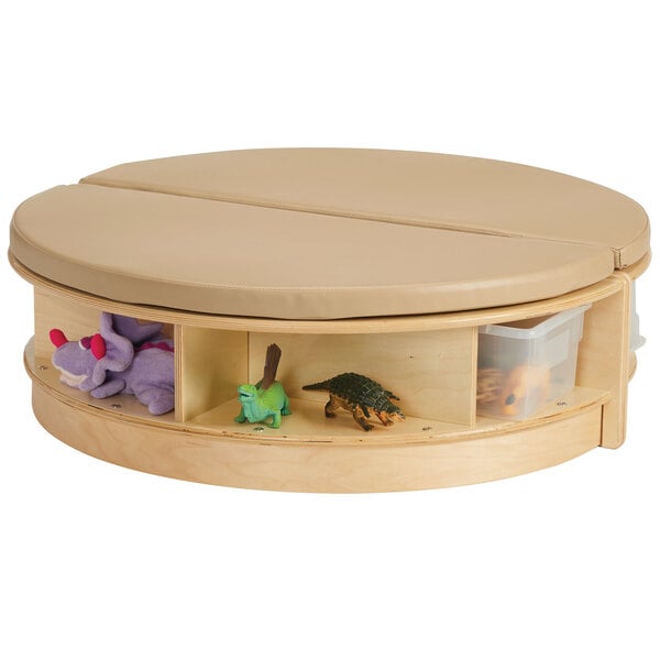 A Jonti-Craft Read-a-Round island table with clear trays and padded seats with stuffed animals inside.