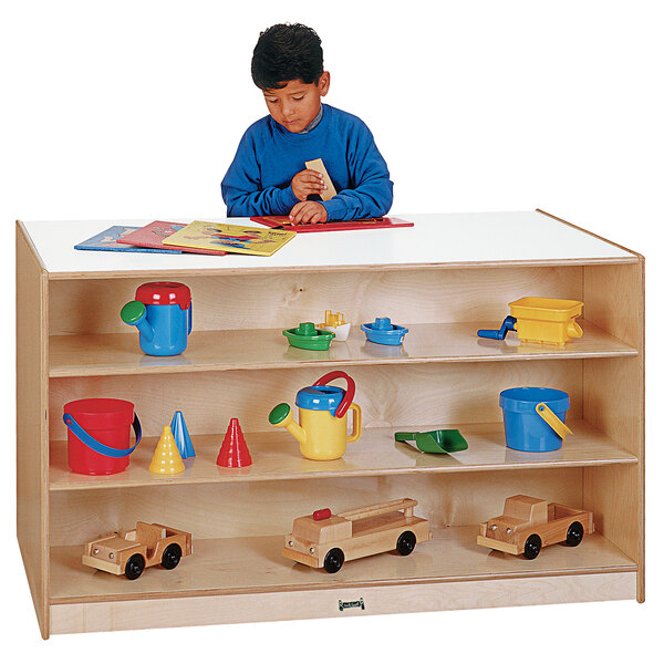 A young boy sitting at a Jonti-Craft mobile storage island with toys.