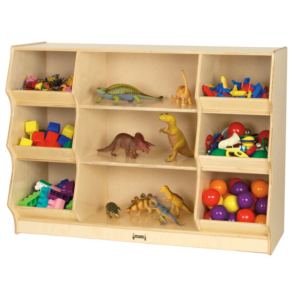 A Jonti-Craft wooden open storage cabinet filled with toys including a toy dinosaur with a red leafy tail.