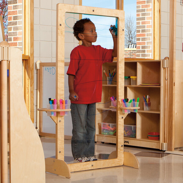 A boy drawing on a Jonti-Craft See-Thru Easel.