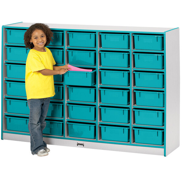 A young girl standing next to a Rainbow Accents teal storage cabinet with blue bins.