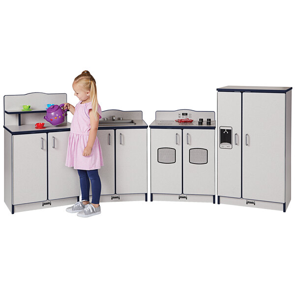 A little girl playing with a Rainbow Accents navy and gray toy kitchen set.