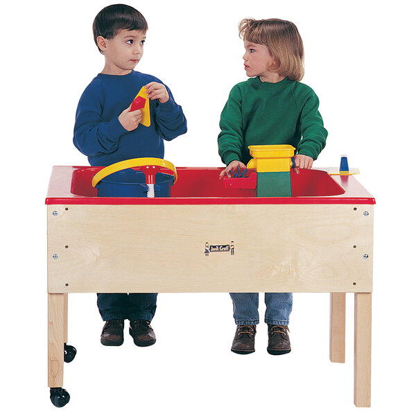 A boy and girl playing with a Jonti-Craft mobile wood sensory table filled with water and toys.