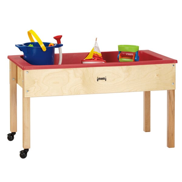 A Jonti-Craft wooden sensory table with toys and a blue bucket with yellow handles.