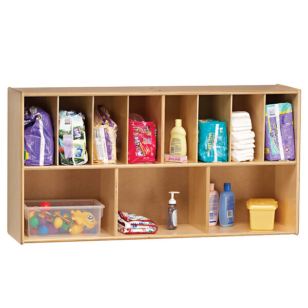 A Jonti-Craft wood wall-mount diaper organizer shelf with diapers and other items on it.