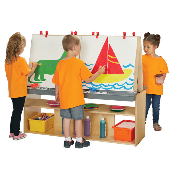 Three children painting on a wooden easel.