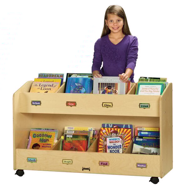 A young girl standing behind a Jonti-Craft 8-section wood book rack.