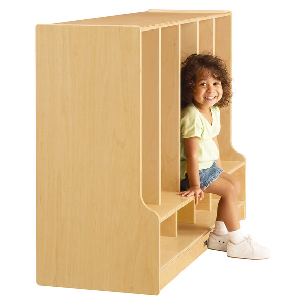 A young girl sitting in a Jonti-Craft toddler-height wooden locker.