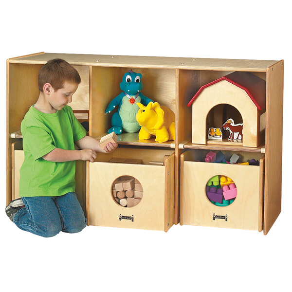 A boy kneeling in front of a Jonti-Craft wood toy storage cabinet with see-through bins.