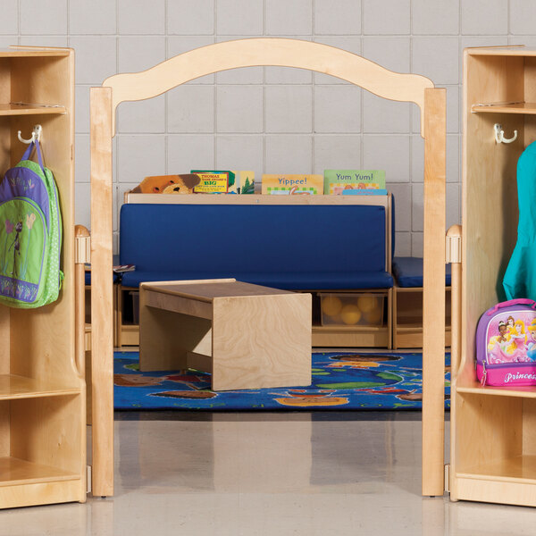 A wooden KYDZ Suite E-Height welcome arch in a room with wooden shelves and a bench.