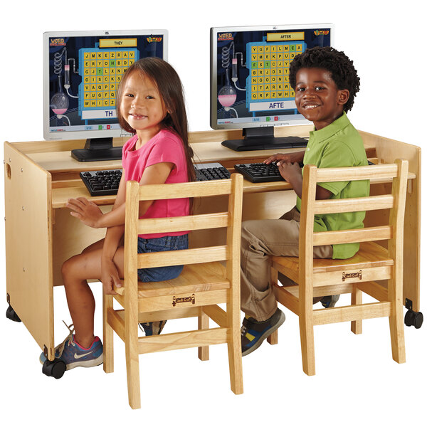 A boy and girl sitting at a Jonti-Craft double computer desk with a young girl using a computer.