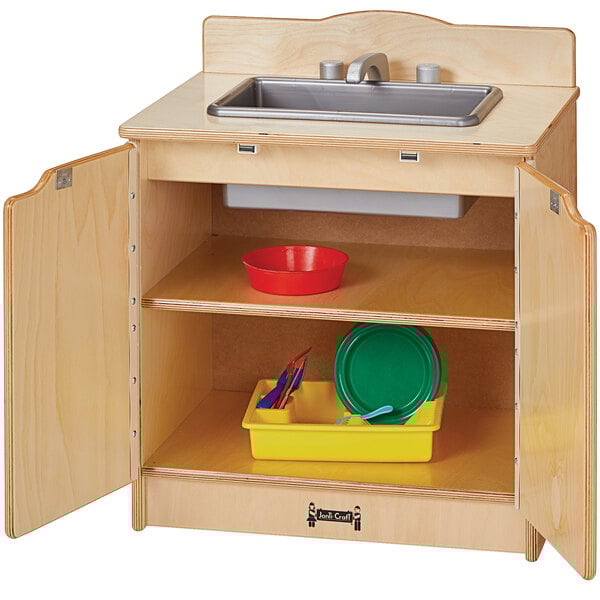 A Jonti-Craft wooden toddler kitchen sink with dishes on a tray.