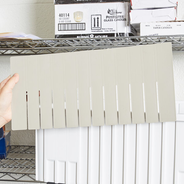 A hand holding a white Short Metro Tote Box Divider package.