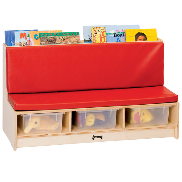 A Jonti-Craft wood literacy couch with red seating and clear tubs above plastic bins filled with books.