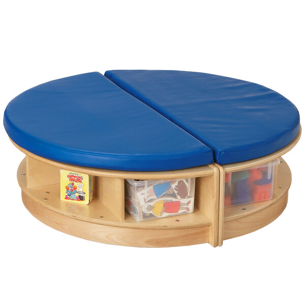 A Jonti-Craft round wood table with blue cushioned seating and clear trays.