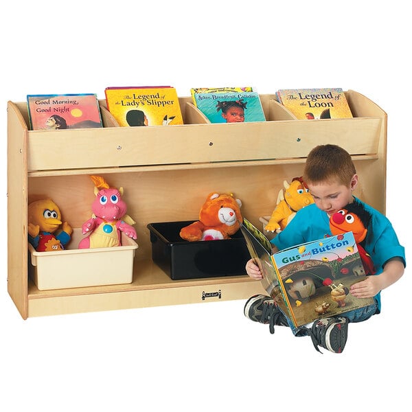 A boy reading a yellow book on a Jonti-Craft book display shelf with a yellow dragon stuffed animal.