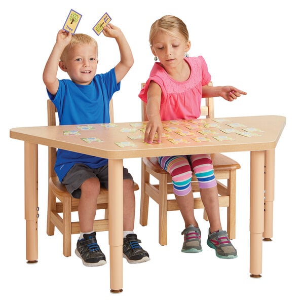 A boy and girl sitting at a Jonti-Craft trapezoid table playing cards.