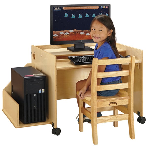 A young girl sitting at a Jonti-Craft wood computer desk with a computer.