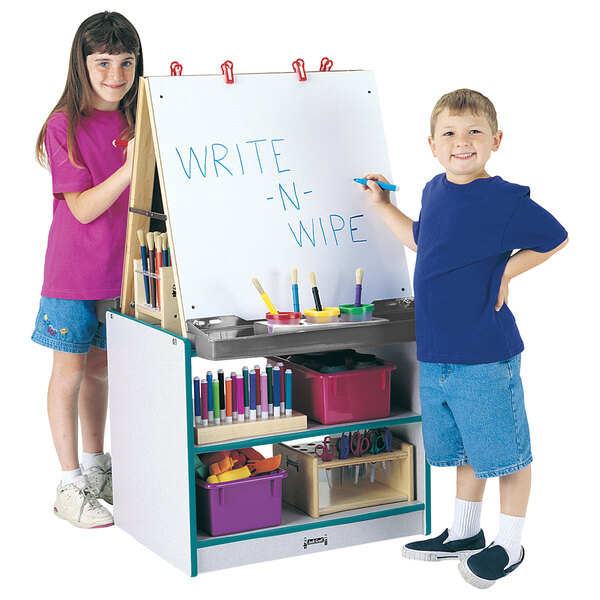 A boy and girl standing at a Rainbow Accents teal and gray art center with a whiteboard.