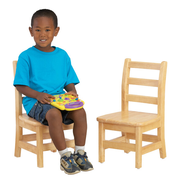A boy sitting on a Jonti-Craft wooden chair holding a toy.
