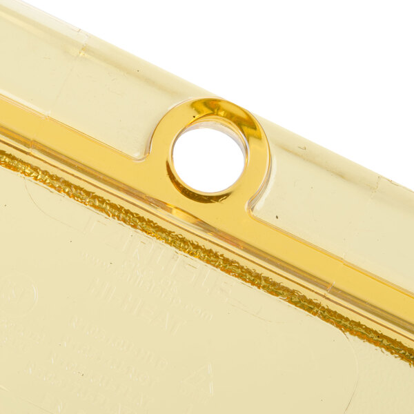 A gold colored Carlisle plastic lid with a spoon notch.