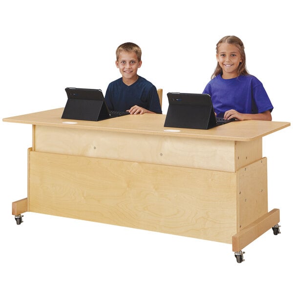 A boy and girl sitting at a Jonti-Craft double computer desk with laptops.