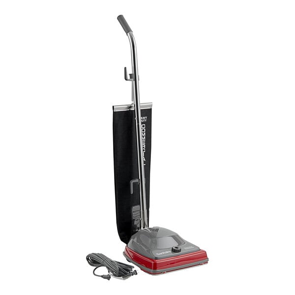 A Sanitaire TRADITION upright vacuum cleaner with a red handle and black cord.