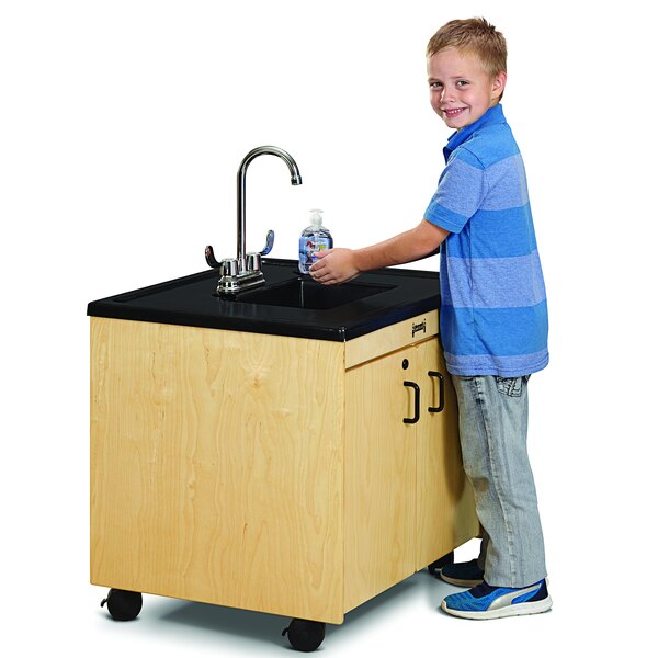 A boy washing his hands in a Jonti-Craft mobile sink.