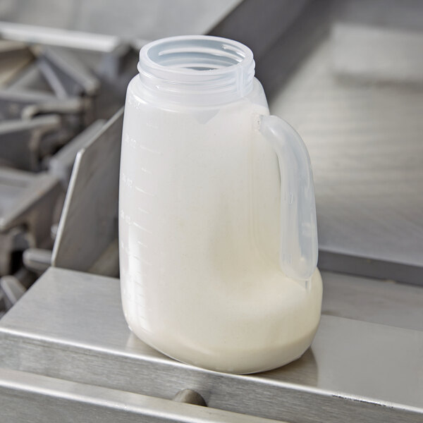 A plastic jug of milk sitting inside a Tablecraft 32 oz. dispenser jar with a handle.
