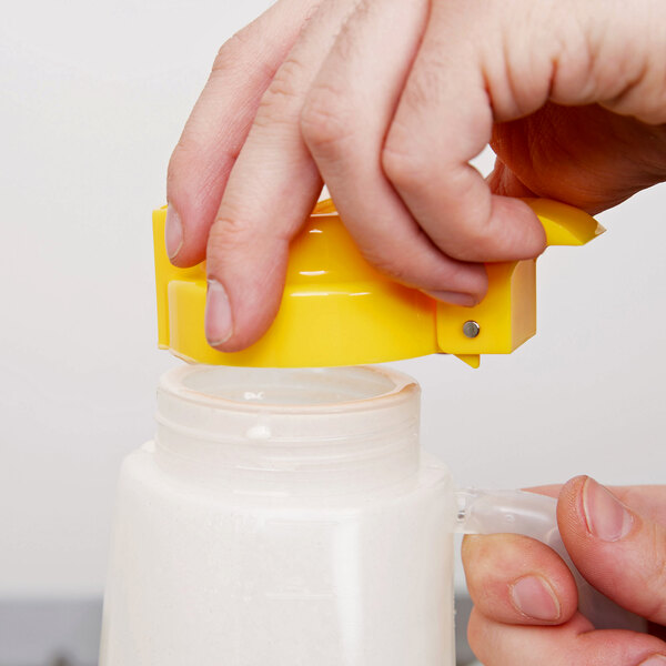 A person using a Tablecraft 32 oz. jar to pour a liquid into a blender.