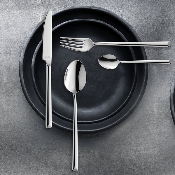 A white plate with a bouillon spoon and silverware on it.