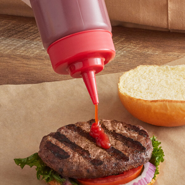 A Tablecraft red squeeze bottle cap pouring ketchup on a burger.