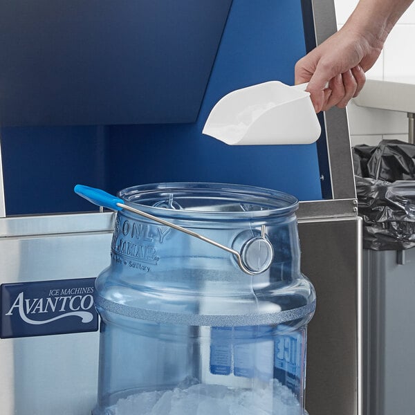 A person using an Avantco ice scoop to pour ice into a clear container.