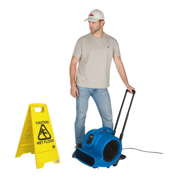 A man standing next to a blue XPOWER air mover with telescopic handle and wheels.